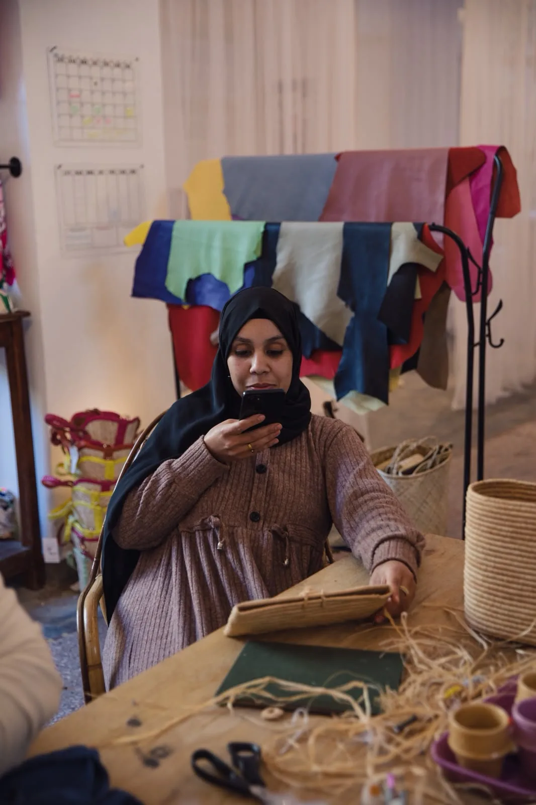 Une artisane YZA à son poste de travail, devant les cuirs teintés de l’atelier