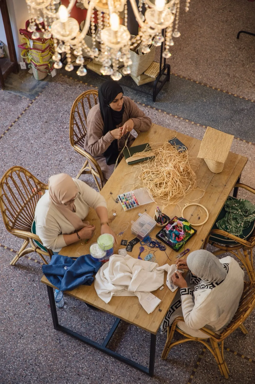 Les artisanes de l’atelier YZA autour de la table de travail, raphia et fils à broder, Guéliz